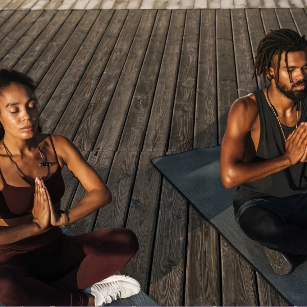 a black woman and a black male practicing yoga